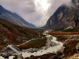 A beautiful aerial view of the Rowaling Valley offers an alpine scenery with snow-capped peaks, lush green meadows, and a trickling river, providing a tranquil and unspoiled paradise for hikers and nature lovers alike.