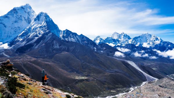 The Annapurna mountain range, with snow-capped peaks against a brilliant blue sky, is seen in a panoramic perspective.