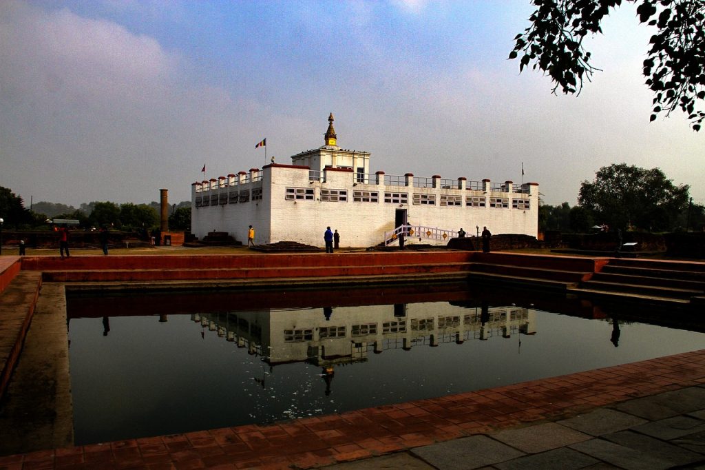 Panoramic view of Lumbini, the birthplace of Buddha, showcasing the sacred Bodhi tree, ancient stupas, and prayer flags against a serene sky