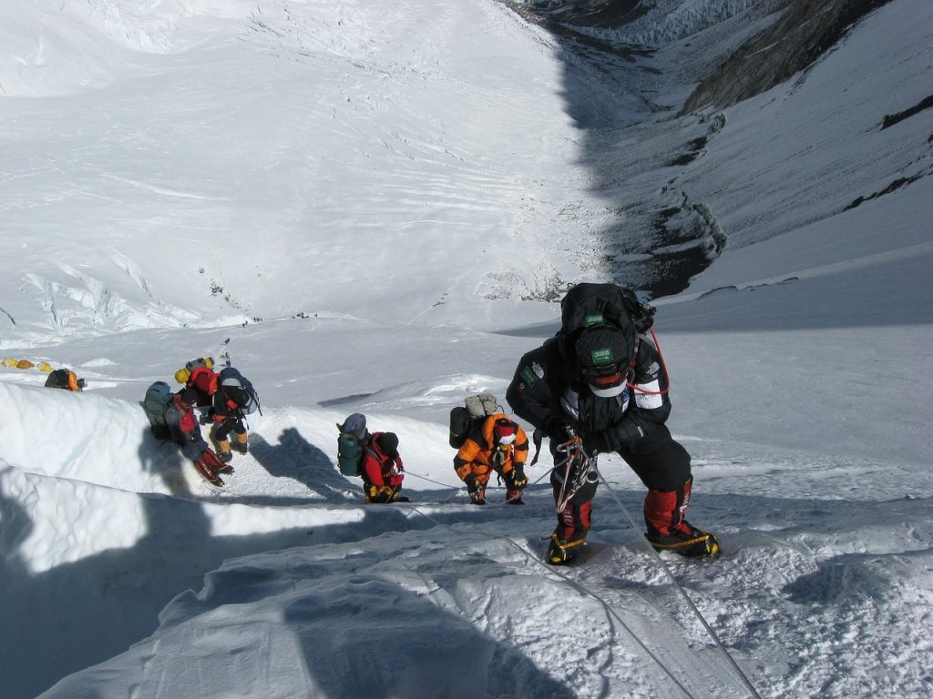 Trekkers ascending Everest using ropes for support.