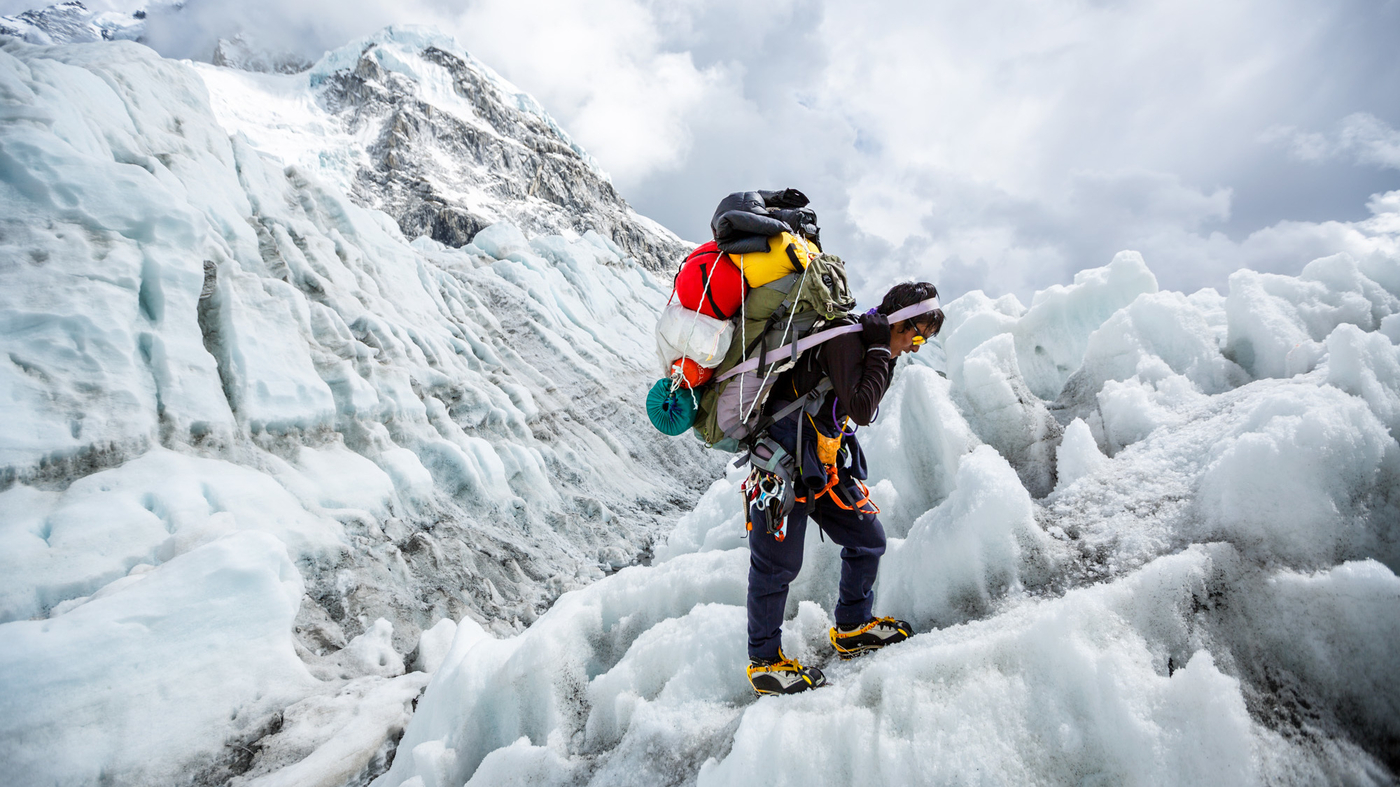 Porter carrying a heavy load of tourist supplies while trekking along the Annapurna trail.