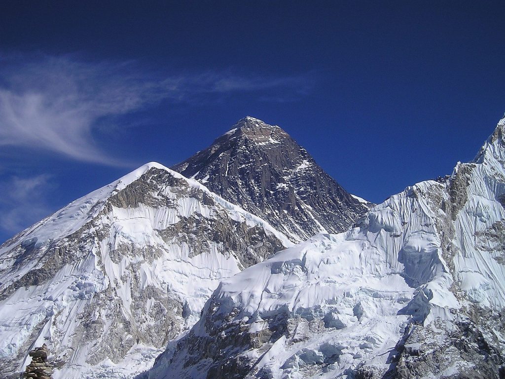 Majestic Mount Everest, the world's highest peak, standing tall amidst the Himalayan range, shrouded in ethereal clouds.