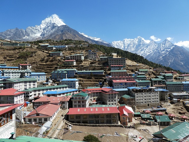 Aerial view of Namche Bazaar, a bustling town surrounded by majestic mountains. Colorful buildings dot the landscape, showcasing the unique blend of Sherpa culture and Himalayan beauty.