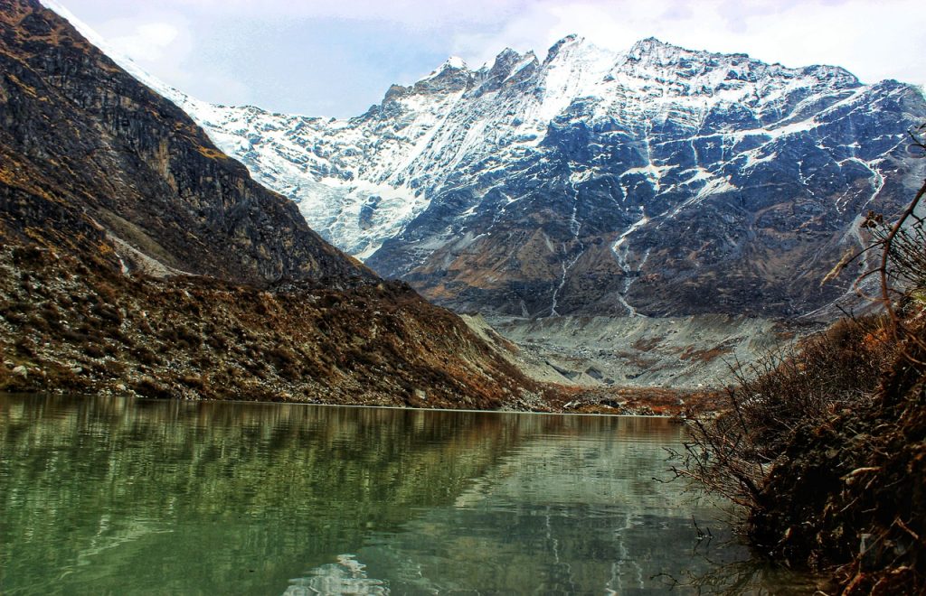 A breathtaking view of Gosaikunda Lake nestled amidst towering snow-capped peaks, surrounded by pristine alpine meadows and reflected in the crystal-clear waters.