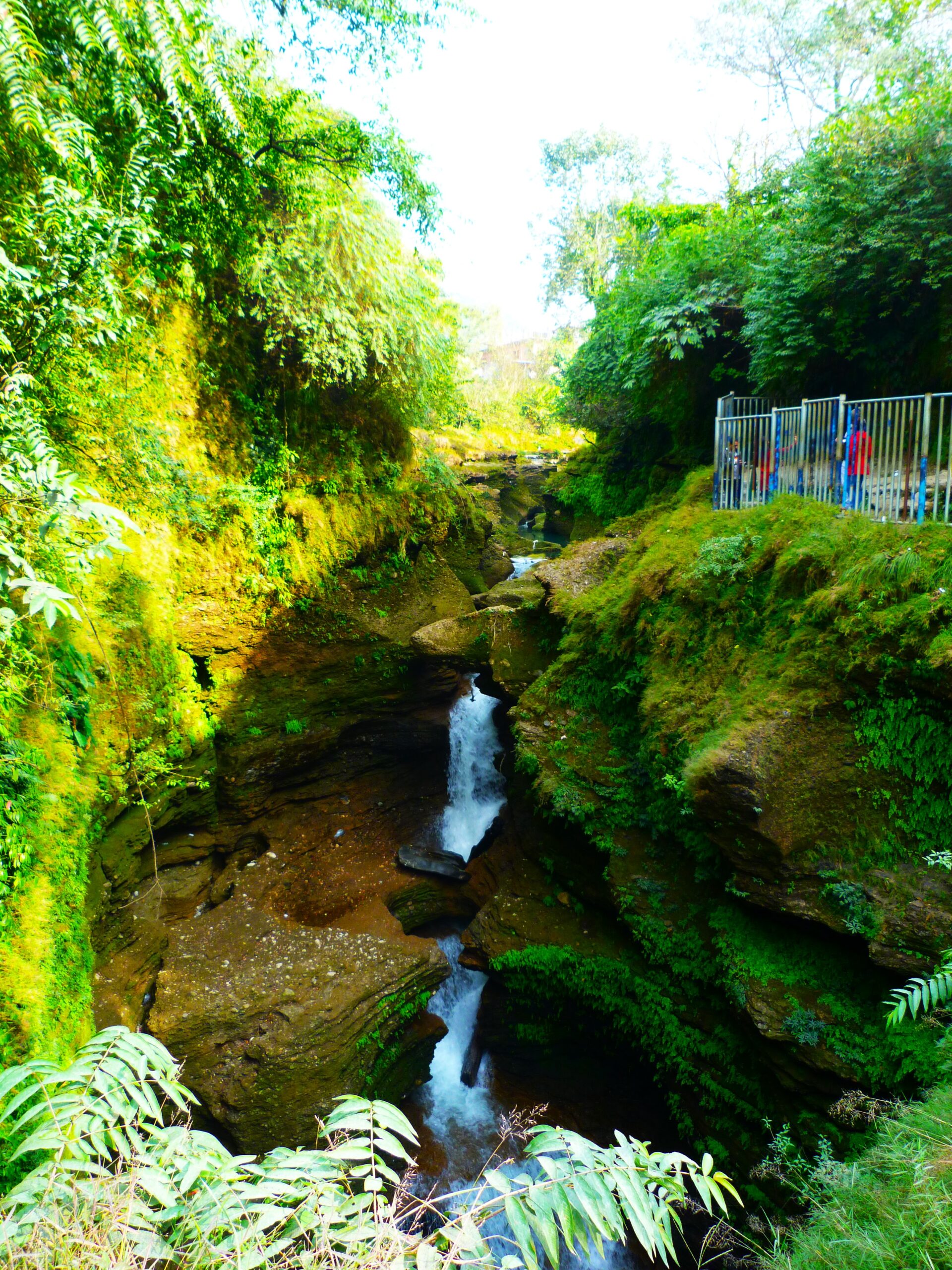 Devi's Fall, also known as Patale Chango, in Pokhara, Nepal. This natural wonder is a breathtaking sight as water plunges into a deep gorge, creating a mesmerizing spectacle surrounded by lush vegetation.