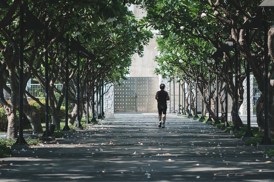 A person running outdoors, wearing athletic gear, with a scenic background, symbolizing exercise and fitness.
