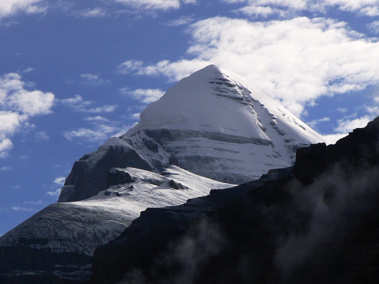 Majestic view of Mount Kailash surrounded by clear skies and rugged terrain.