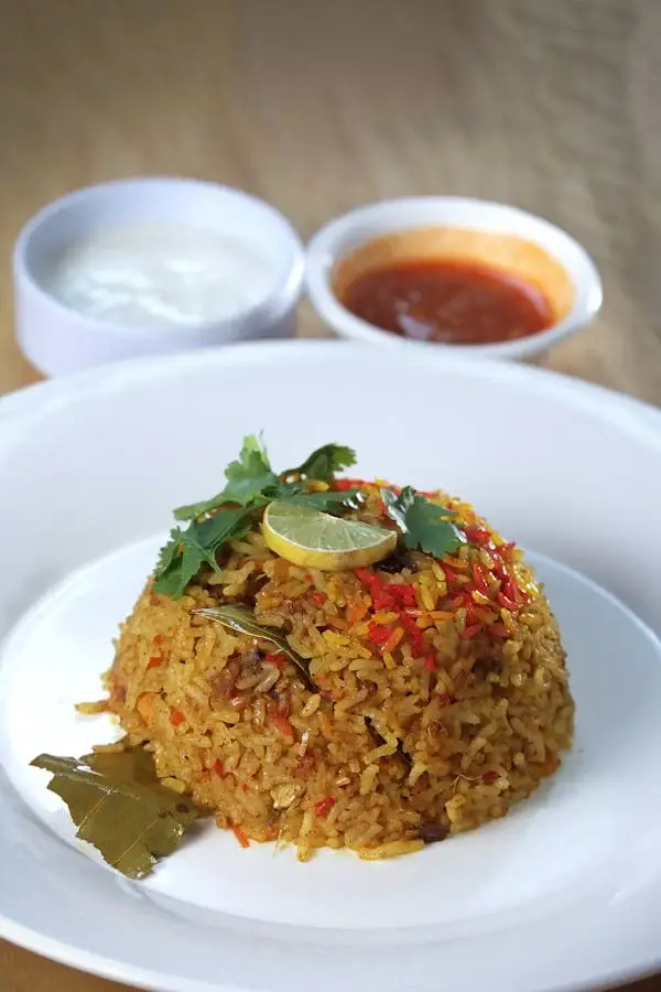 Plate of colorful fried rice with vegetables and herbs.