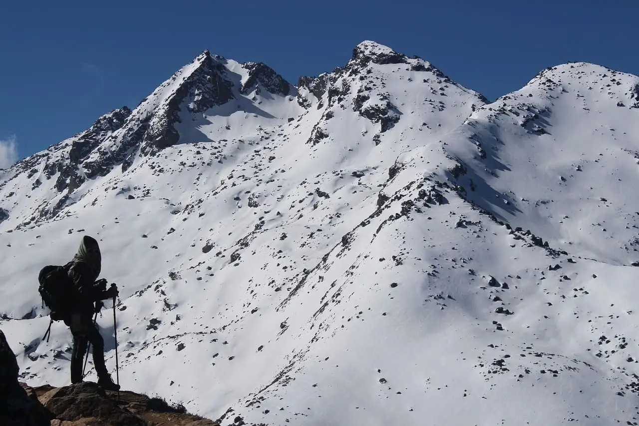 A trekker standing in front of a majestic Himalayan mountain in Nepal, performing the Namaste gesture a beautiful moment that highlights cultural respect and helps travelers connect using Common Nepali Words and Phrases.